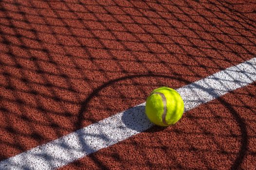 Shadows of net and racket surrounding a tennis ball on a white line on an outdoor court in sunshine in a sport and active lifestyle concept