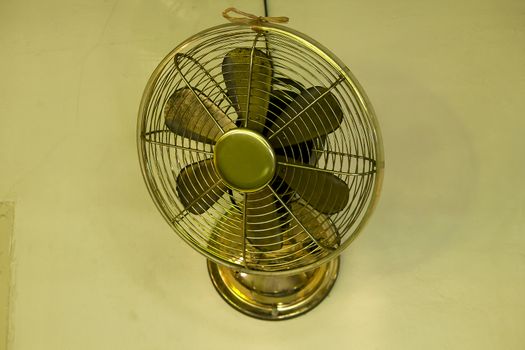 Old brass fan mounted on the cement wall.