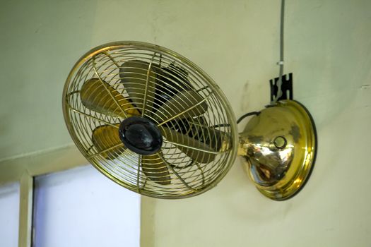 Old brass fan mounted on the cement wall.