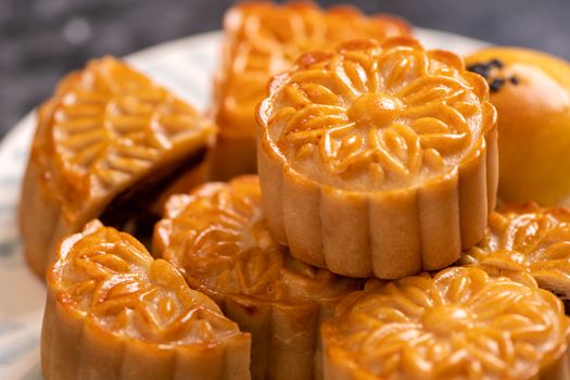 Tasty baked egg yolk pastry moon cake for Mid-Autumn Festival on black slate dark background. Chinese festive food concept, close up, copy space.