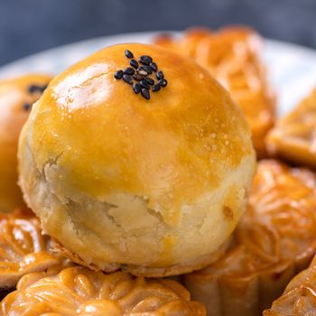 Tasty baked egg yolk pastry moon cake for Mid-Autumn Festival on black slate dark background. Chinese festive food concept, close up, copy space.