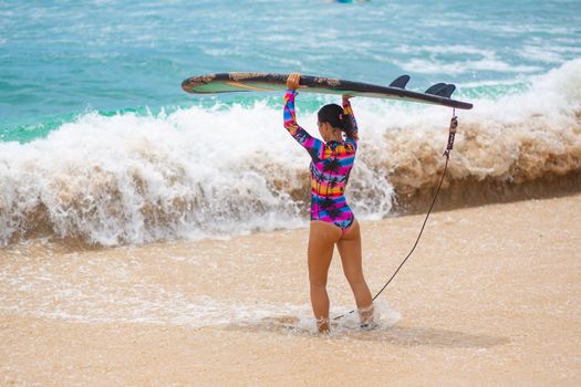 Sexy slim girl with surf board on tropical sand beach. Healthy active lifestyle in summer vocation