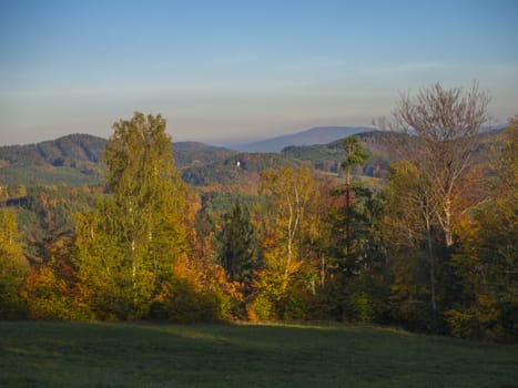 green meadow with autumn colorful forest and trees and hills before sunset landscape in luzicke hory mountain