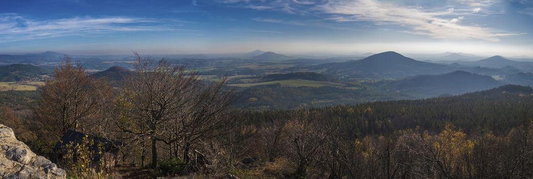 Luzicke hory wide panorama, panoramic view from Hochwald Hvozd one of the most attractive view-points of the Lusatian Mountains with autumn colored deciduous and coniferous tree forest and green hills, golden hour light.