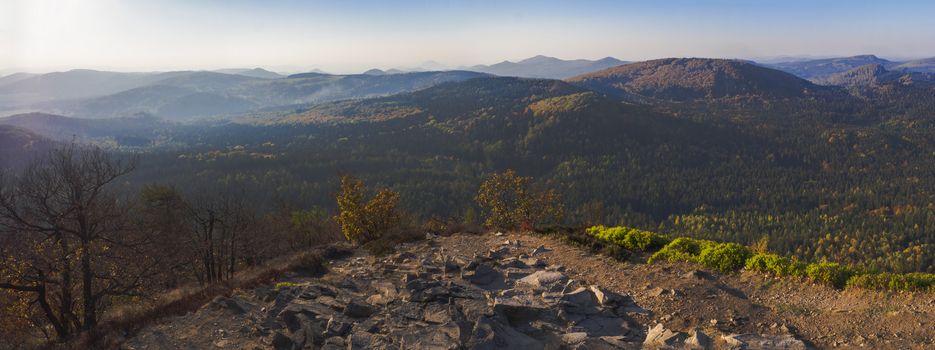 Lusatian Mountains or luzicke hory wide panorama, panoramic view from Klic or Kleis one of the most attractive view-points of the Lusatian Mountains with autumn colored deciduous and coniferous tree forest and green hills, golden hour light.