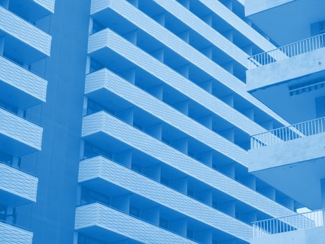 blue toned abstract image of large modern highrise modern apartment buildings with angular balconies