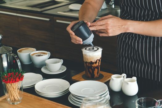 close-up photo of the hand is pouring freshly made cappuccino into a glass. barista Professional men making latte and espresso for customer service.  coffee shop owner is preparing drinks in the cafe.