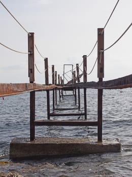 a perspective view of an abandoned broken rusty iron jetty running into to sea