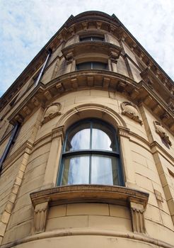 perspective view of a 19th century tall stone neoclassical building with ornate curved windows in the little germany business district of bradford west yorkshire