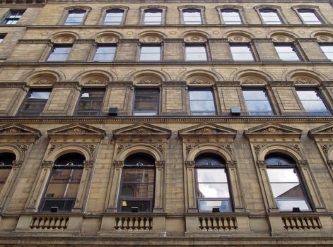 the facade of a large stone 19th century commercial building in the little germany area of bradford west yorkshire with ornate neo classical style windows