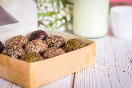 Healthy snack. Energy ball with date plam, black and white sesame, chia and rasin in paper box on wooden table. Vegan vegetarian.