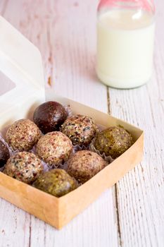 Healthy snack. Energy ball with date plam, black and white sesame, chia and rasin in paper box on wooden table. Vegan vegetarian.