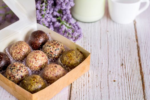 Healthy snack. Energy ball with date plam, black and white sesame, chia and rasin in paper box on wooden table. Vegan vegetarian.