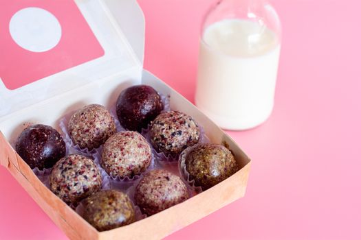 Healthy snack. Energy ball with date plam, black and white sesame, chia and rasin in paper box on pink background. Vegan vegetarian.
