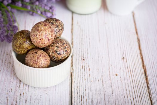 Healthy snack. Energy ball with date plam, black and white sesame, chia and rasin in ceramic bowl on wooden table. Vegan vegetarian.