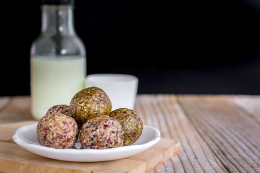 Healthy snack. Energy ball with date plam, black and white sesame, chia and rasin in ceramic palte on table. Vegan vegetarian.