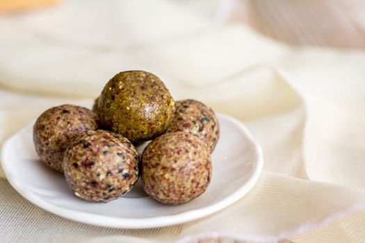 Healthy snack. Energy ball with date plam, black and white sesame, chia and rasin in ceramic palte on table. Vegan vegetarian.