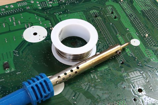 soldering iron on green mainboard for repairing electronic of the computer circuit board concept technology of computer circuit hardware
