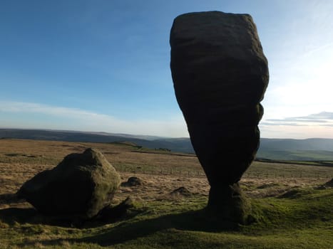 the great bridestone a large natural monolithic rock formation on west yorkshire moorland near todmorden in shadow against a bright blue sky