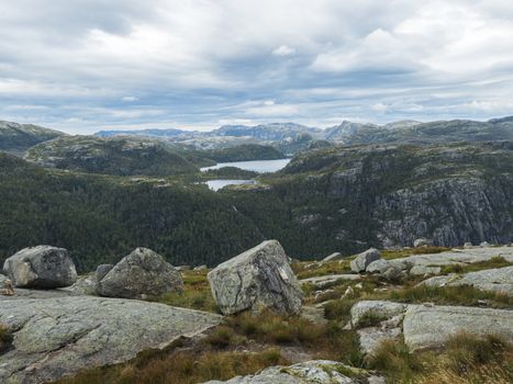 View on landscape with rock,blouders, stone and Lysefjord on hike to Preikestolen massive cliff famous Norway viewpoint Moody sky, autumn day. Nature and travel background, vacation and hiking holiday