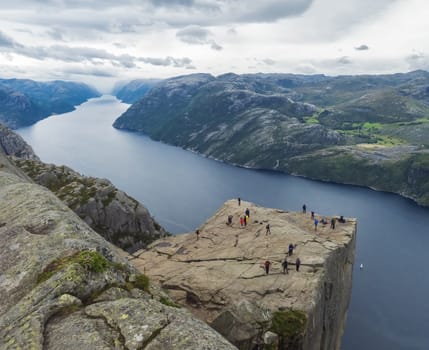 Preikestolen massive cliff at fjord Lysefjord, famous Norway viewpoint with group of tourists and hikers.Moody autumn day. Nature and travel background, vacation and hiking holiday concept