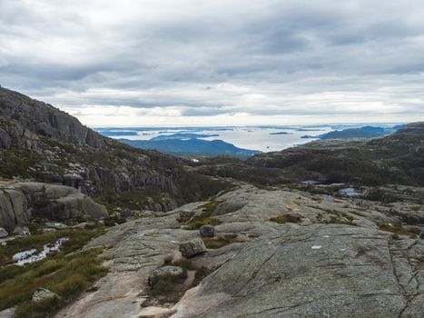 View on landscape with rock,blouders, stone and Lysefjord on hike to Preikestolen massive cliff famous Norway viewpoint Moody sky, autumn day. Nature and travel background, vacation and hiking holiday
