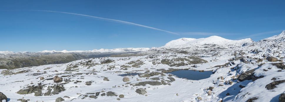 Wide Panoramic view from Krossbu on glacier Smorstabbreen, snow-capped mountains and blue lakes in Jotunheimen National Park, Western Norway.