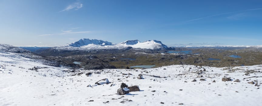 Wide Panoramic view from Krossbu on glacier Smorstabbreen, snow-capped mountains and blue lakes in Jotunheimen National Park, Western Norway.