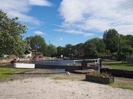 a view of the lock gates at brighouse basin on the calder and hebble navigation canal with barges and canalside buildings surrounded by trees
