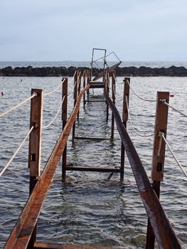 a perspective view of an abandoned broken rusty iron jetty running into to sea