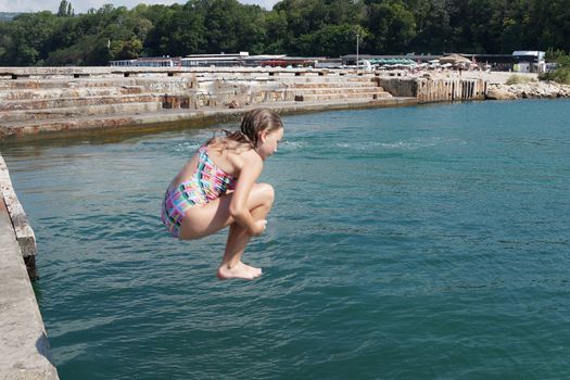 girl jumping into the sea from the pier