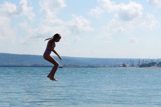 girl jumping into the sea from the pier