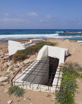 the entrance to an old abandoned concrete military bunker on the beach at paphos cyprus