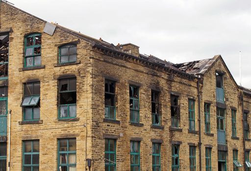 the broken roof and broken windows in a large burned out old industrial building after a fire