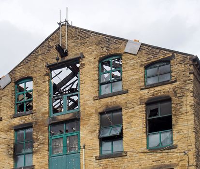 the broken roof and broken windows in a large burned out old industrial building after a fire