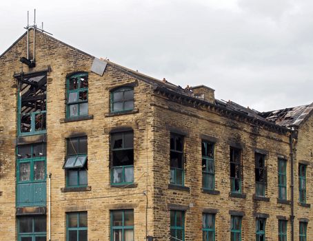 the broken roof and broken windows in a large burned out old industrial building after a fire