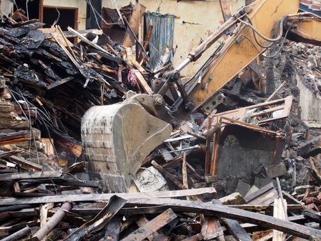 Hydraulic crusher excavator backoe machinery working on a demolition site clearing debris