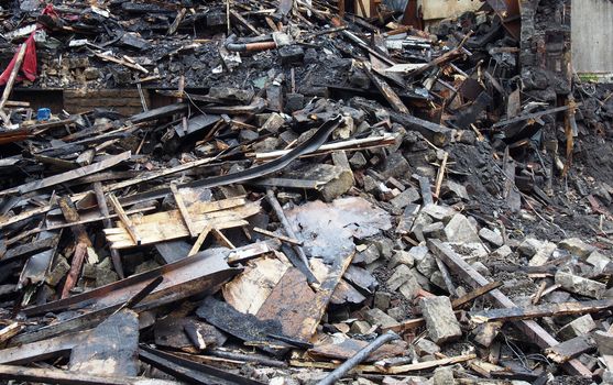 black burned timbers and walls in a collapsed house destroyed by fire