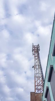 Mobile phone radio antenna tower. Cell tower against a cloudy sky, vertical photo.