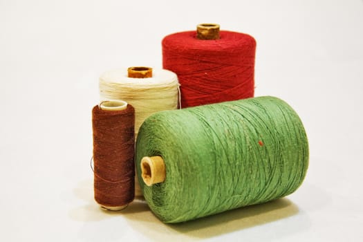 Spools of thread of different colors on a white background