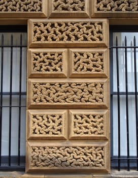 close up of ornately carved large stone blocks on an old building surrounded by windows with iron bars