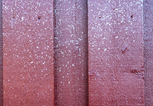 Close up view at multiple small white spots of white paint accidentally sprayed at red wooden wall.