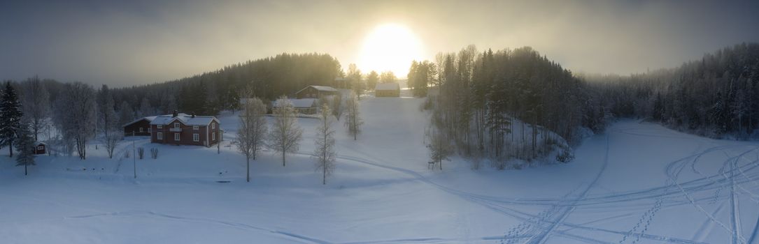 Majestic view of winter sunset with very large sun spot in frozen foggy air, winter pine tree forest, aerial, Grano village, around Umea city, Northern Sweden, short winter day, subarctic landscape.