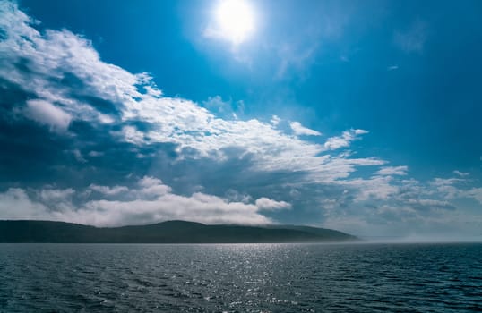 Sea fog laying over the sea disappears under strong morning sun, almost no wind, blue skies