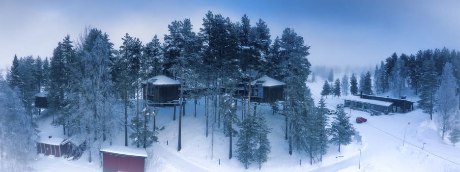 GRANO, SWEDEN FEBRUARY 08, 2020: Aerial view at bird’s nest up high in the tree canopy, houses of Grano Beckasin, tourist place at shores of beautiful Umeriver winter foggy nature, Subarctic Sweden