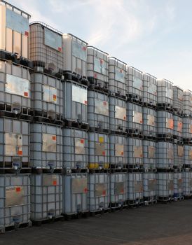 metal framed intermediate bulk containers stacked on pallets waiting to be cleaned or reused in an industrial yard