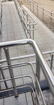 Close-up, entrance to the building with a wheelchair ramp and metal handrails, outdoor, vertical photo.