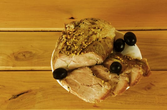 Baked ham on a plate on a wooden surface

