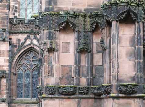 details of ornately carved medieval stonework with niches and animals on the facade of chester cathedral
