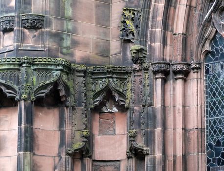 details of ornately carved medieval stonework with niches and faces on the facade of chester cathedral